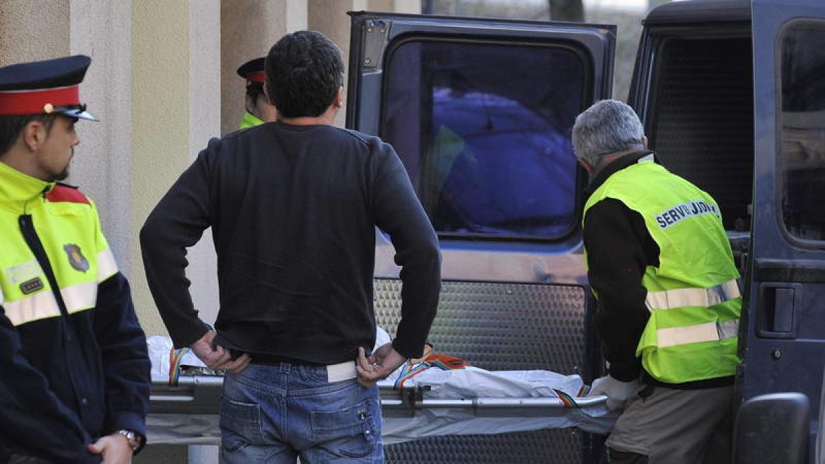 Las fuerzas de seguridad trasladan el cadáver de la joven.