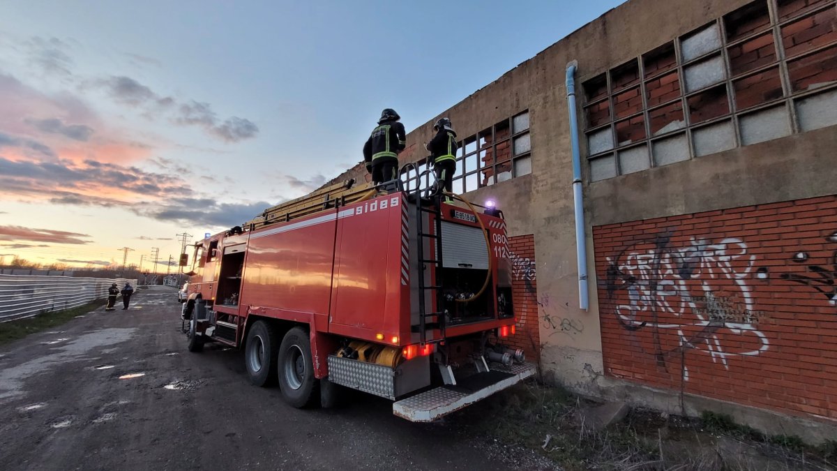 Un vehículo de los bomberos junto a la nave abandonada que ayer se incendió en Villabalter. BOMBEROS DE LEÓN