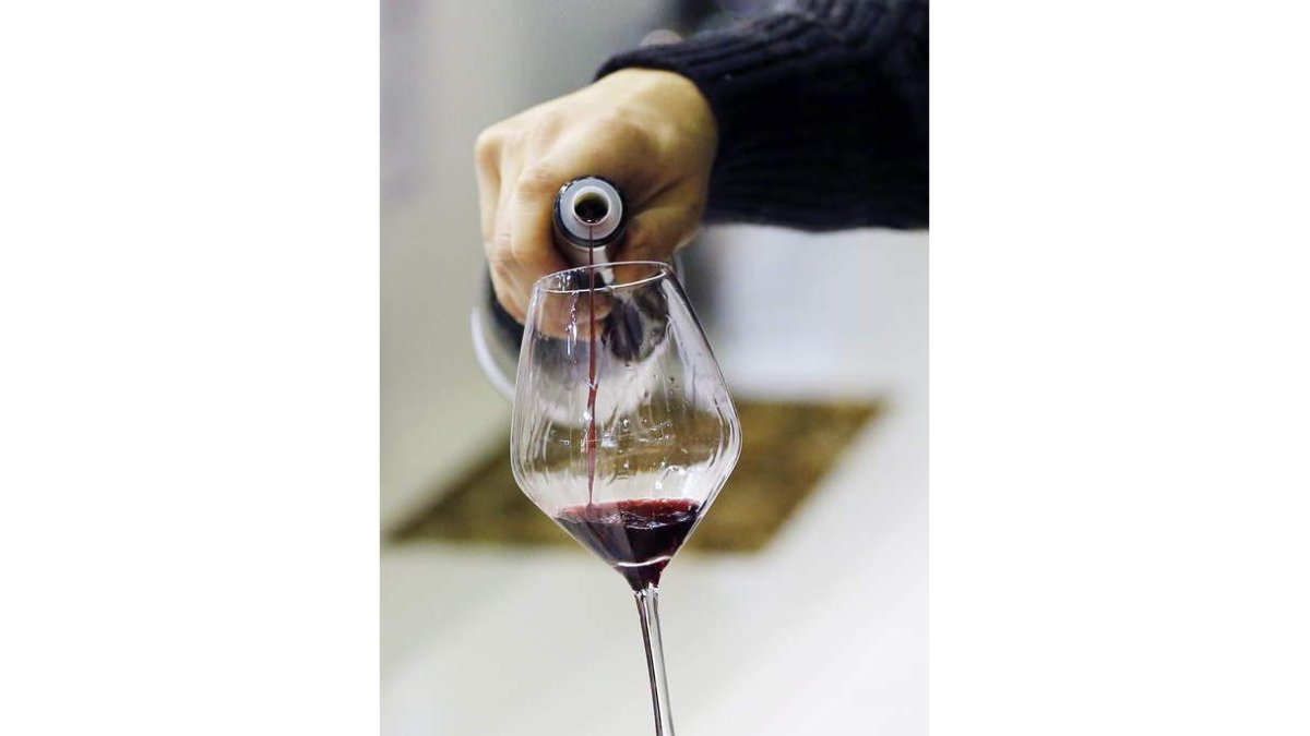Un hombre se sirve vino en una copa.