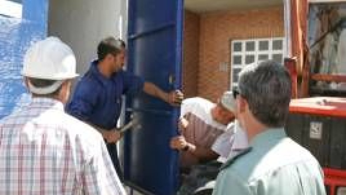 Operarios sellando la puerta ante la mirada del responsable de Unión Fenosa y un guardia civil