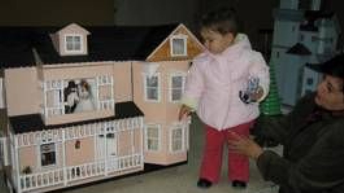 Una niña observa una casa de muñecas perteneciente a la exposición de maquetas