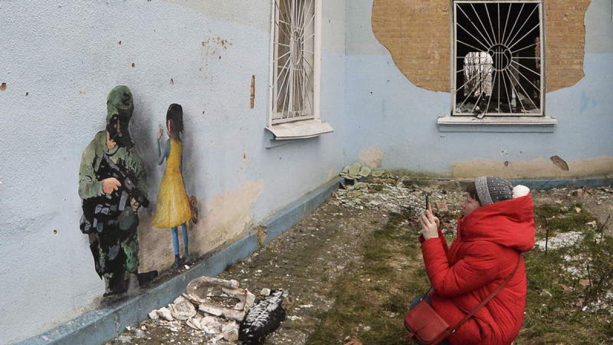 Una mujer fotografía una pintura en un muro de Jarkov. ANDRII NESTERENKO
