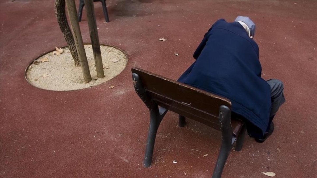 Un anciano, sentado solo en el banco de un parque de Barcelona.