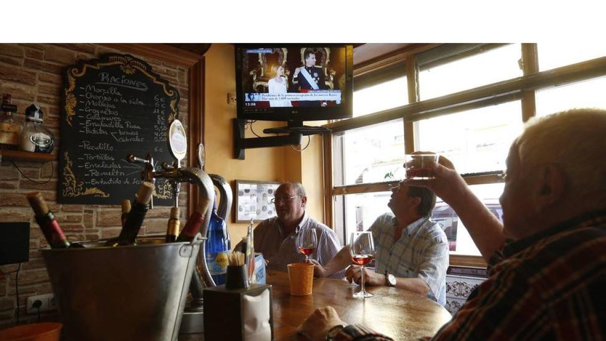 Un grupo de leoneses brinda por el nuevo rey mientras ven en la televisión del bar el acto de proclamación