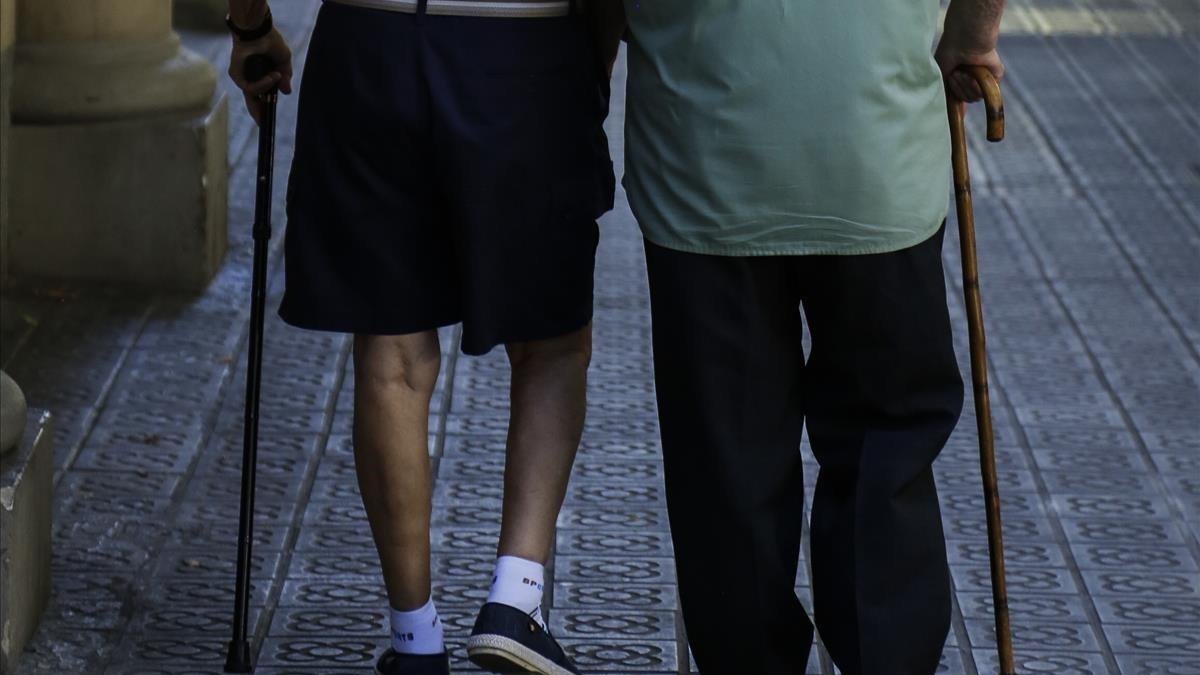 Dos ancianos pasean por una calle.