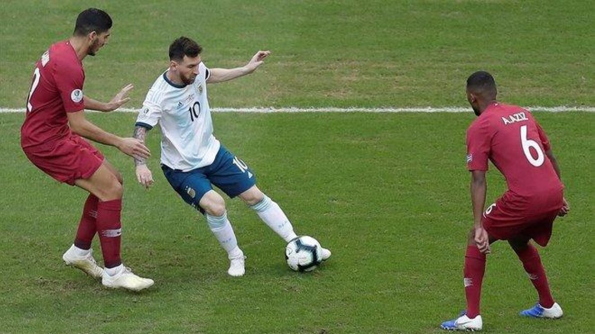 Messi controla un balón, vigilado por jugadores de Qatar.