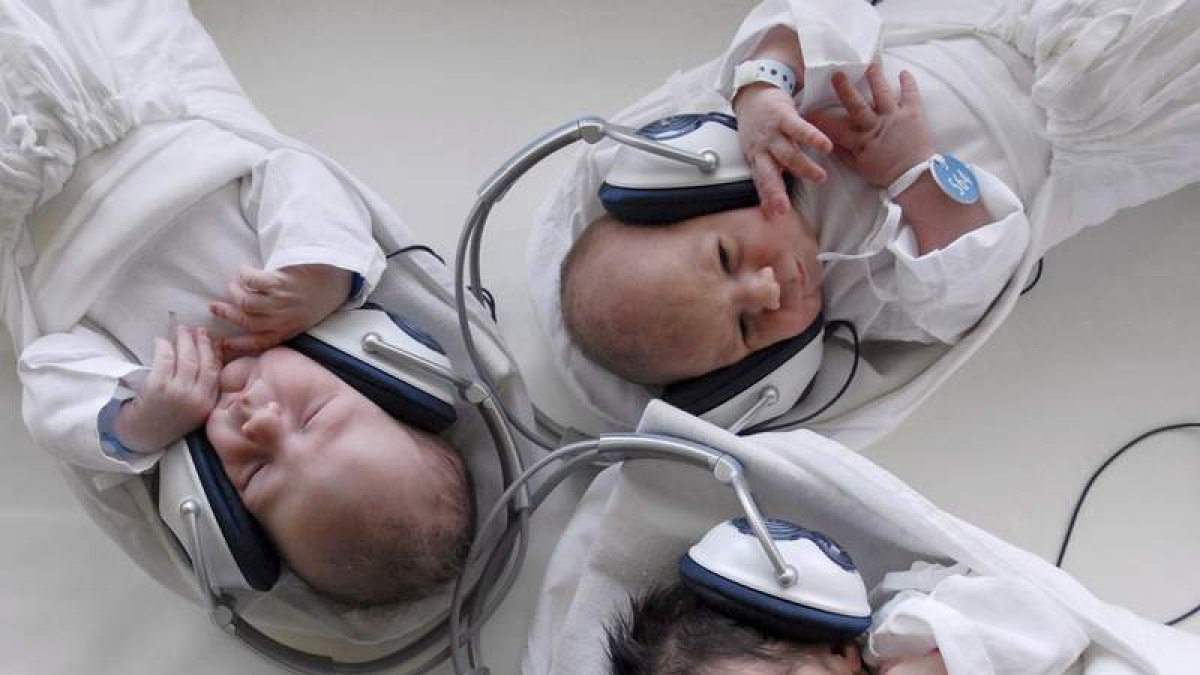 Bebés recién nacidos escuchan música con auriculares en un hogar maternal.