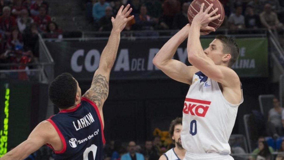 El madridista Carroll lanza a canasta en presencia del base de Baskonia, Larkin