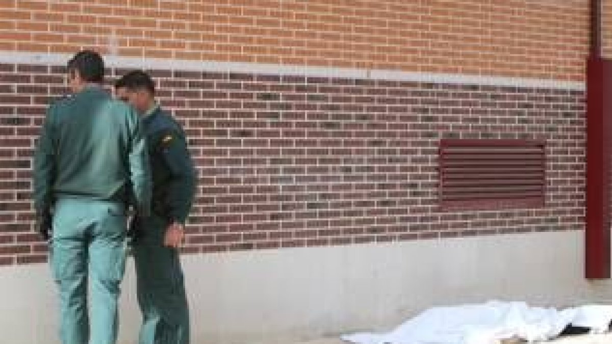 Los agentes observan las marcas de los disparos en la pared del edificio con el cadáver a su espalda