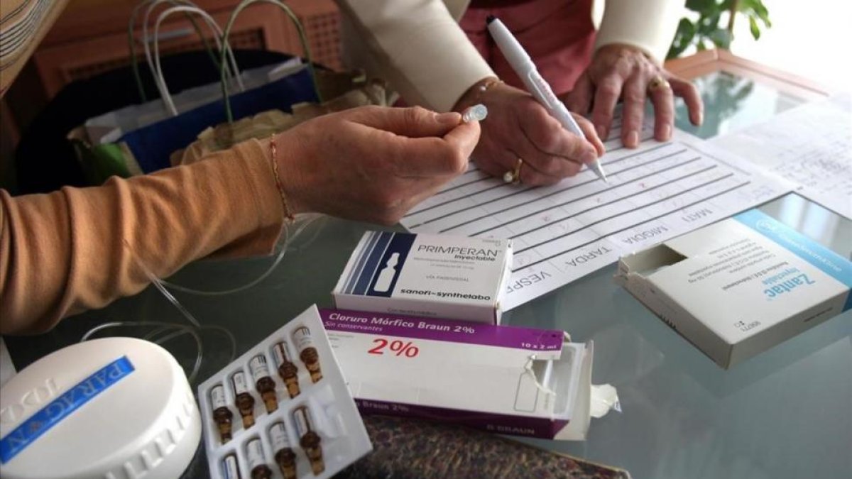 Dos enfermeras preparando los medicamentos para muerte digna en casa de un paciente.