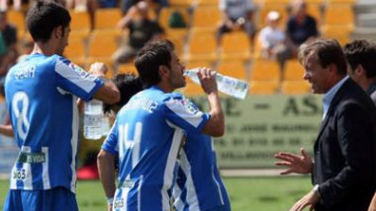 Los jugadores de la Deportiva reciben instrucciones mientras se refrescan en la banda.