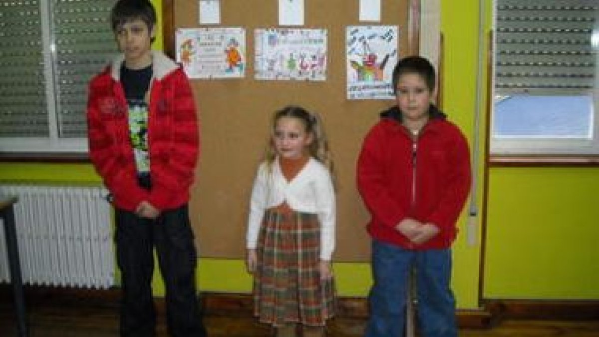 Los tres finalistas del concurso posan delante de sus trabajos, colgados en la pared