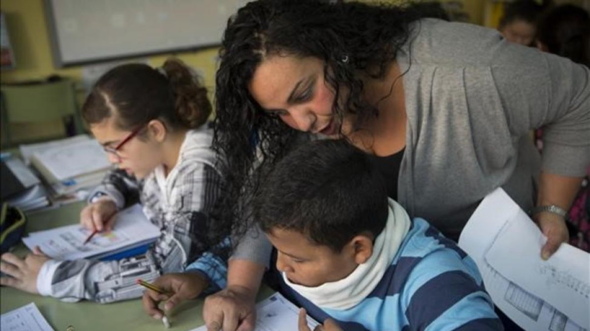 Una madre ayuda a un alumno de primaria en la comunidad de aprendizaje del colegio Joaquim Ruyra de L'Hospitalet de Llobregat.