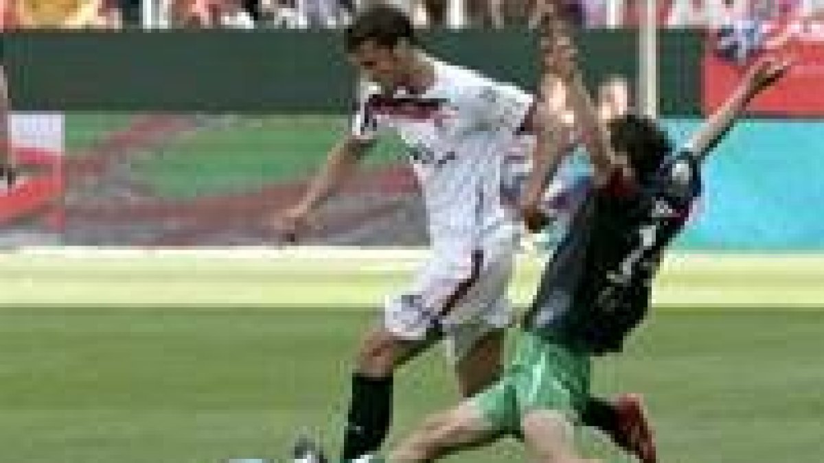 El defensa del Racing Pinillos intenta frenar al jugador sevillista Puerta