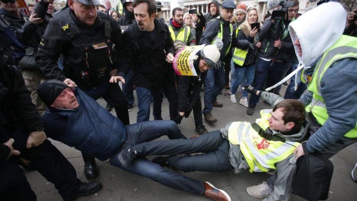 La policía británica y otros manifestantes separan a un partidario y un detractor del brexit en una marcha en Londres.