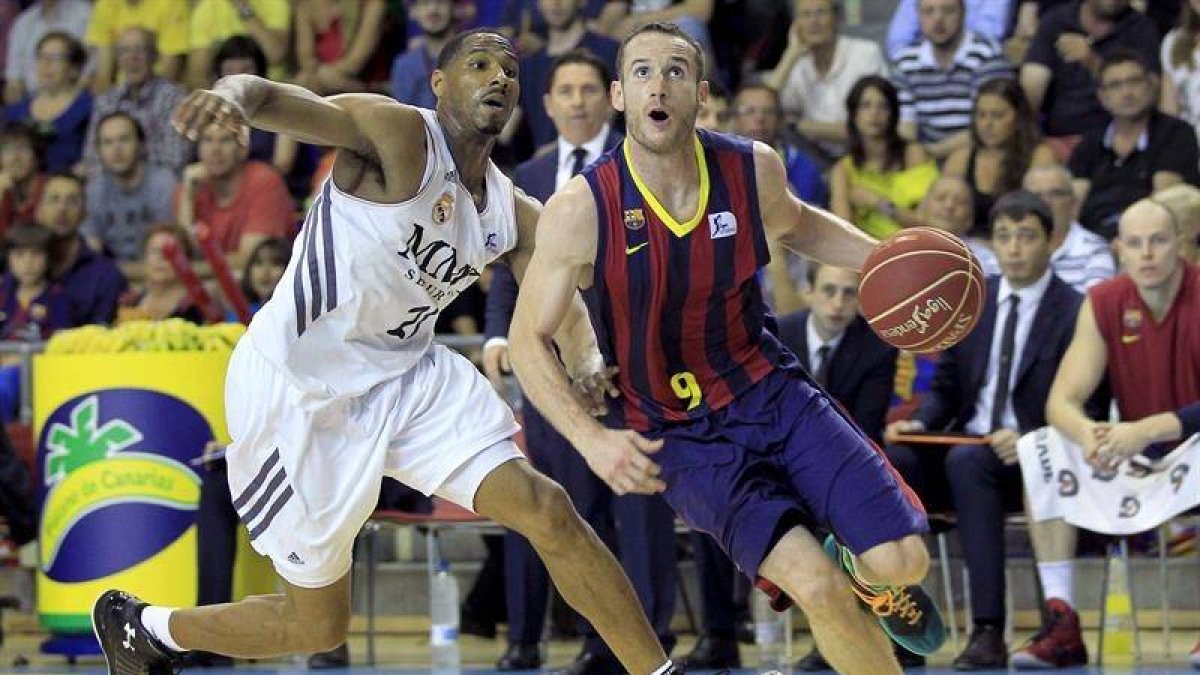 El base brasileño del FC Barcelona Marcelinho Huertas (d) avanza ante la defensa del alero estadounidense del Real Madrid Tremmell Darden (i), durante el tercer partido del Play Off por el título de la Liga ACB jugado esta tarde en el Palau Blaugrana de B