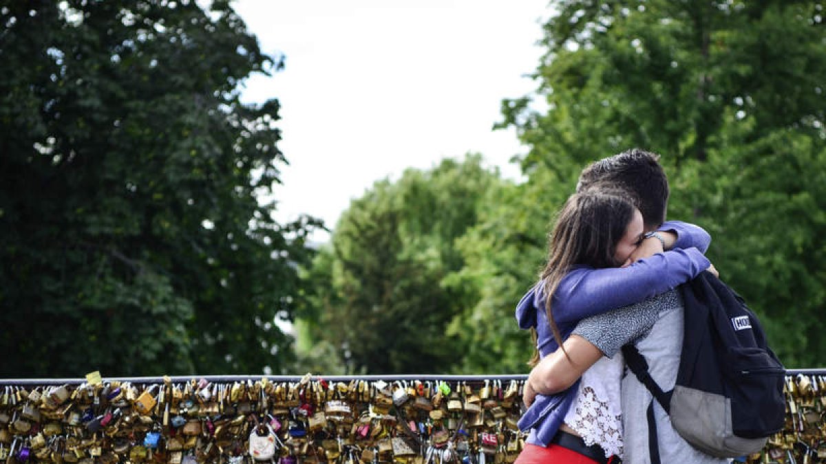 Una pareja se abraza tras colocar un candado en un puente en París. SANDRA JABALERA