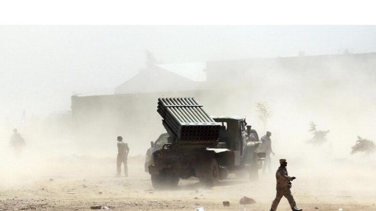 Rebeldes libios caminan por un campo en Bani Walid, Libia.