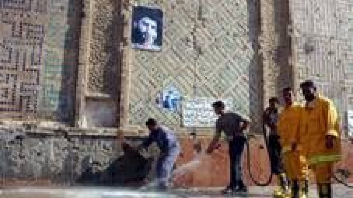 Barrenderos municipales de Nayaf limpian los restos de la batalla a la puerta de la Gran Mezquita
