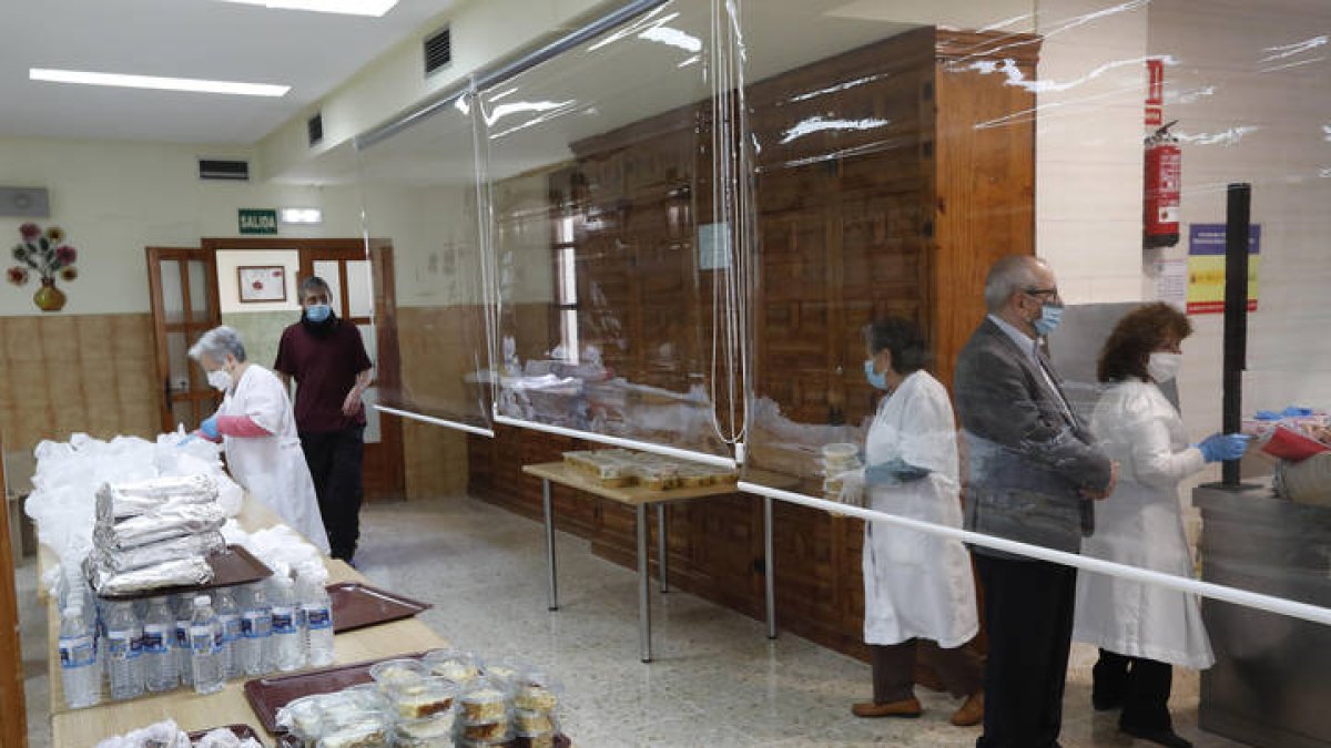 Personas voluntarias preparan bolsas que repartirán a los usuarios. El centro tiene ya adaptadas sus instalaciones para atender de forma presencial. FERNANDO OTERO