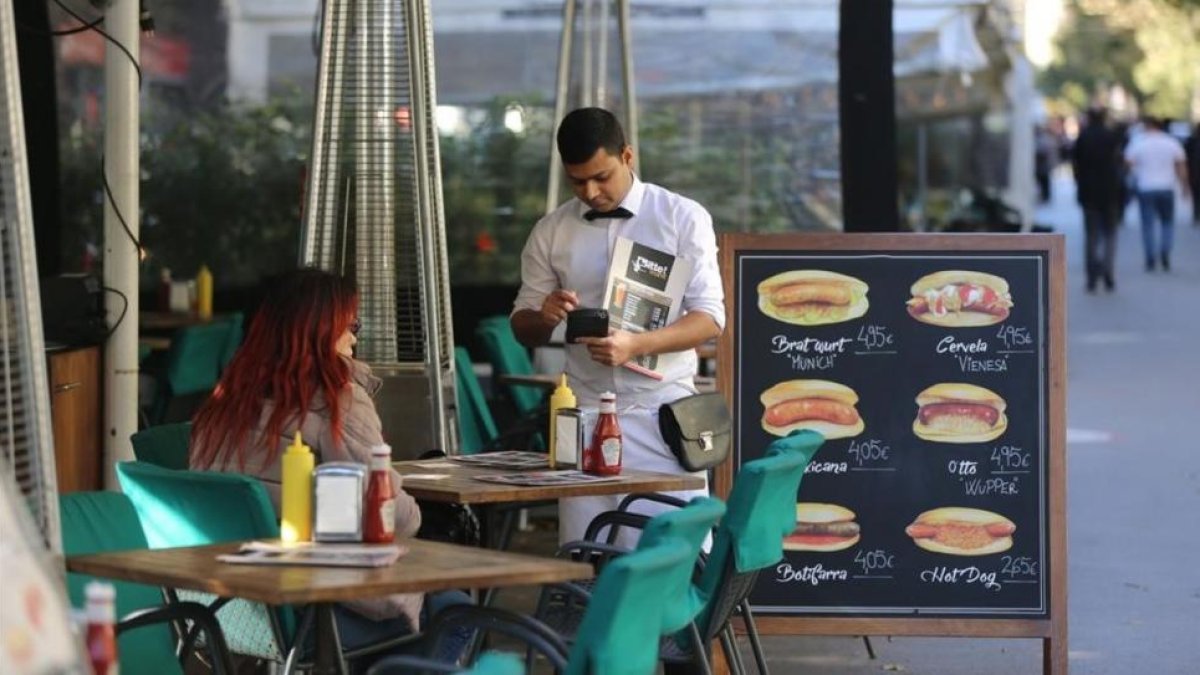 Un camarero sirve a unos clientes en una terraza.