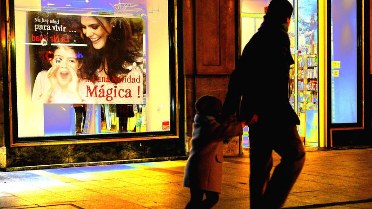 Un hombre pasa con un niño por delante de una tienda. RAMIRO