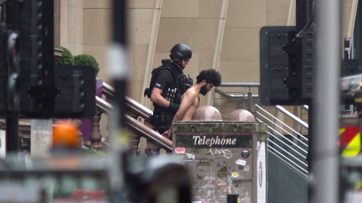 Imagen de un policía británico con uno de los detenidos tras el ataque en el hotel de Glasgow. STRINGER