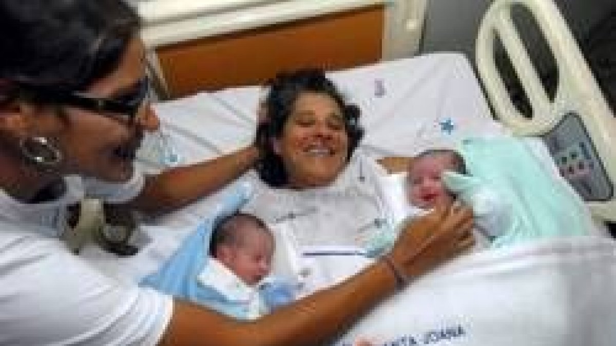 La brasileña Rozinete Cláudia Michelle mira a sus hijos y a su madre, en la cama tras dar a luz