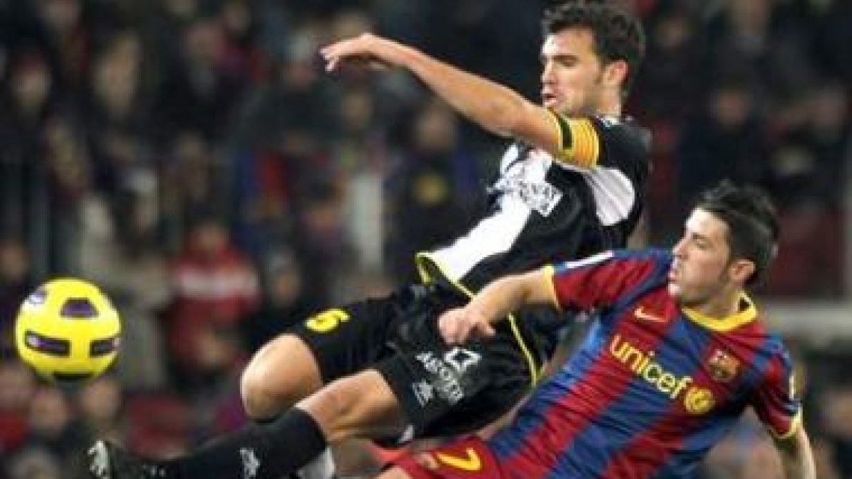 El delantero del Barcelona David Villa pugna por un balón con el defensa del Levante Miguel Robusté