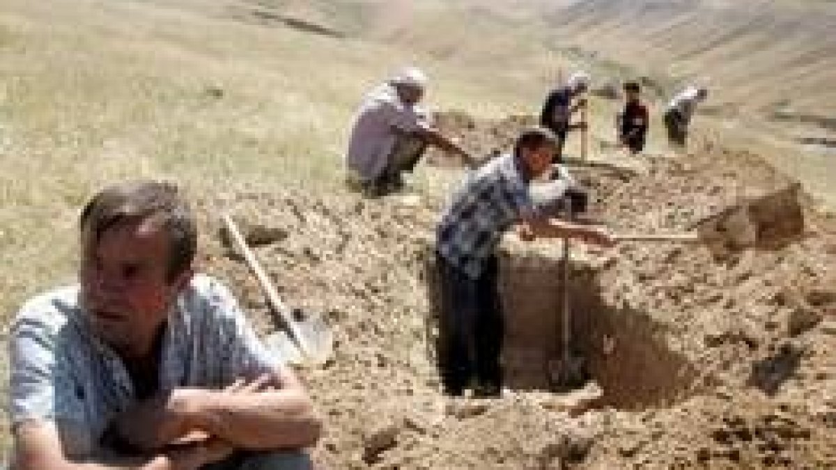 Un grupo de hombres cavan fosas en un monte a las afueras de Andizán