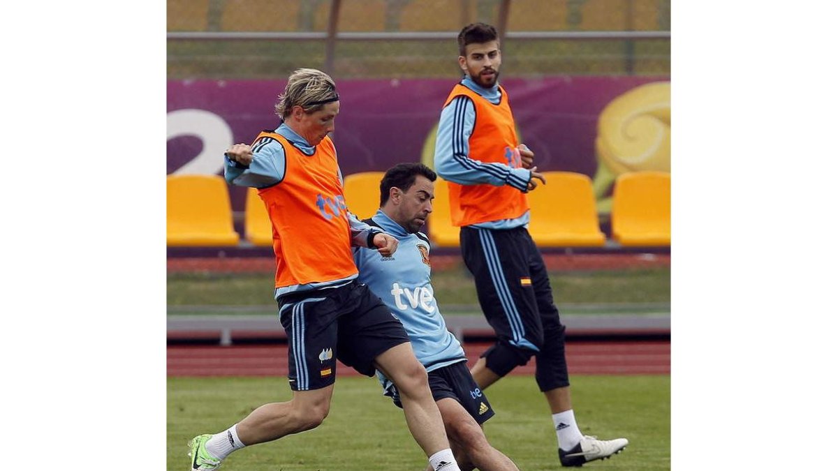 Xavi y Torres pugnan por la pelota, con Piqué al fondo, en el entrenamiento de España.