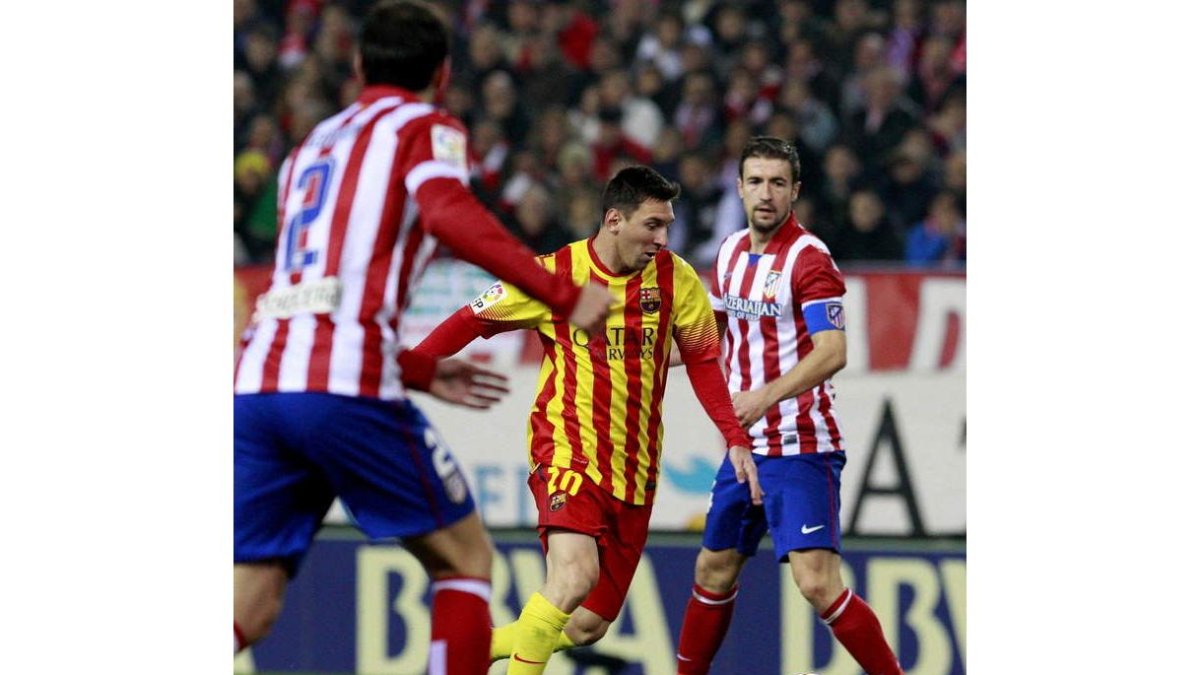 Messi controla un balón rodeado por jugadores del Atlético de Madrid.