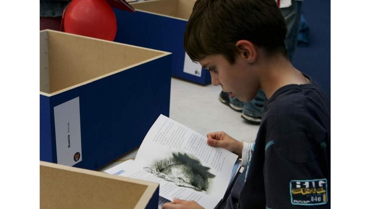 Un niño lee un libro en una feria de la capital leonesa. RAMIRO