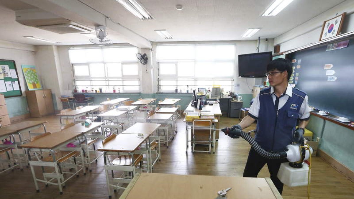 Un empleado desinfecta un aula de una escuela primaria de Seúl.