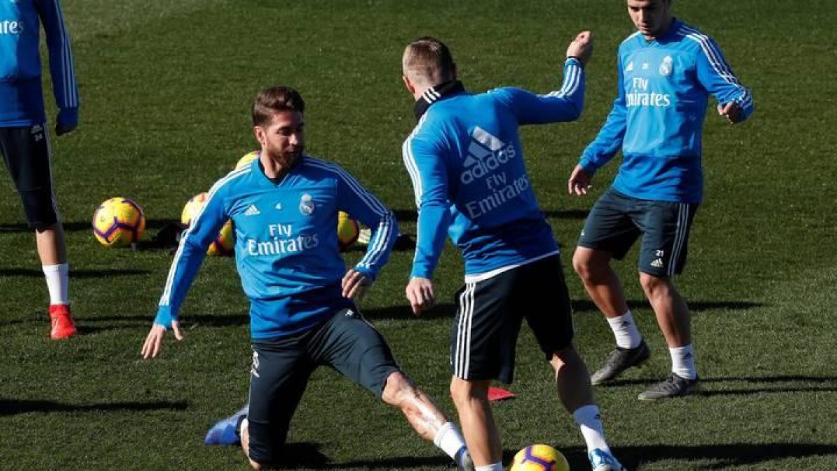 Los jugadores del Real Madrid Sergio Ramos (i) y Toni Kroos (d), durante el entrenamiento realizado esta mañana en la Ciudad Deportiva de Valdebebas para preparar el partido de Liga de mañana frente al Girona.