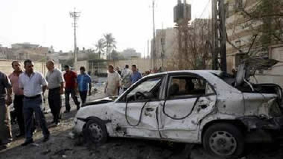 Dos hombres observan los daños de un coche junto a la catedral católica de Sayidat al-Nejat