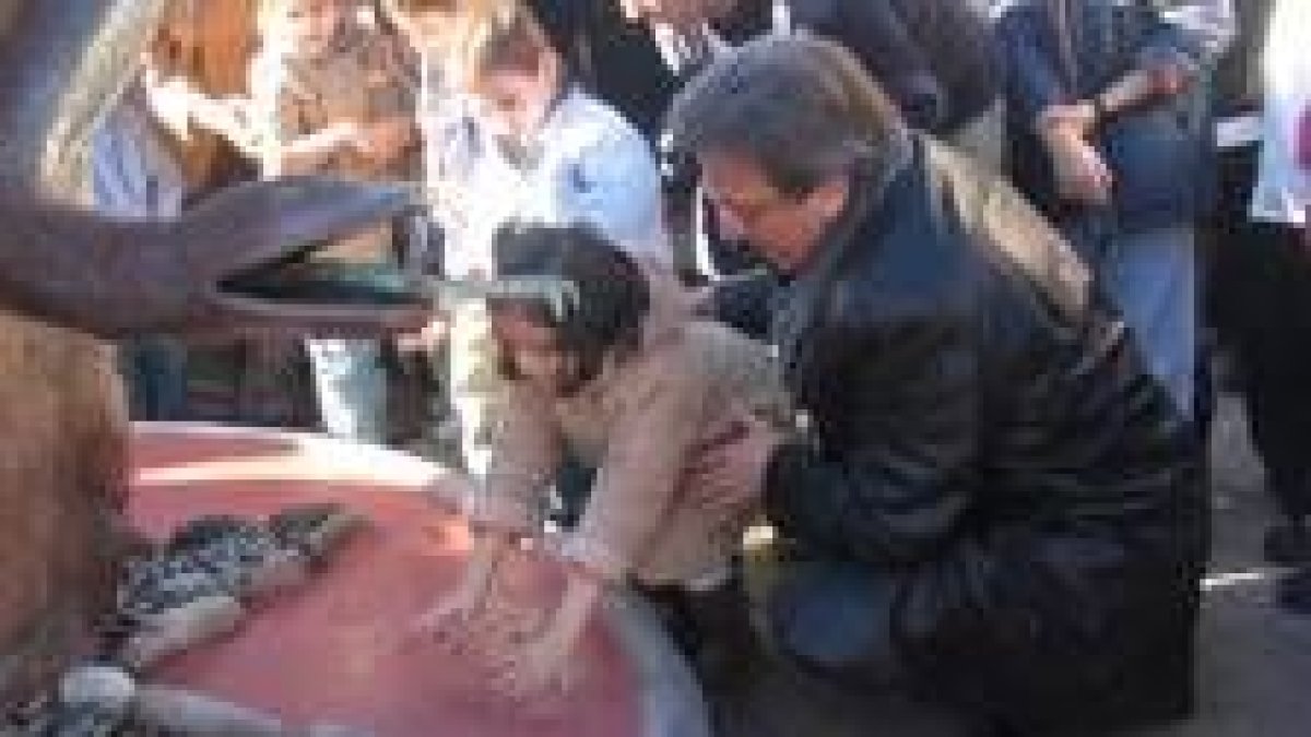 El alcalde sostiene a una de las niñas que dejaron sus huellas en el monumento