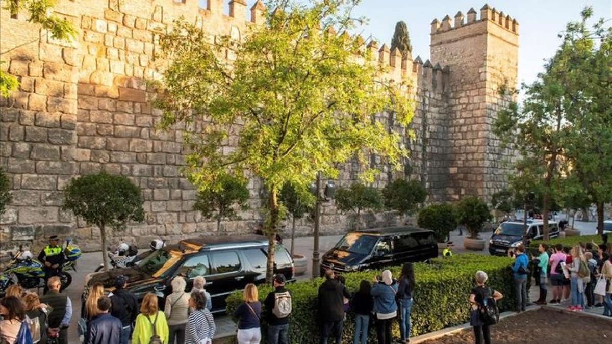 Un grupo de personas ve desfilar a la comitiva de Obama al llegar a los Alcázares.