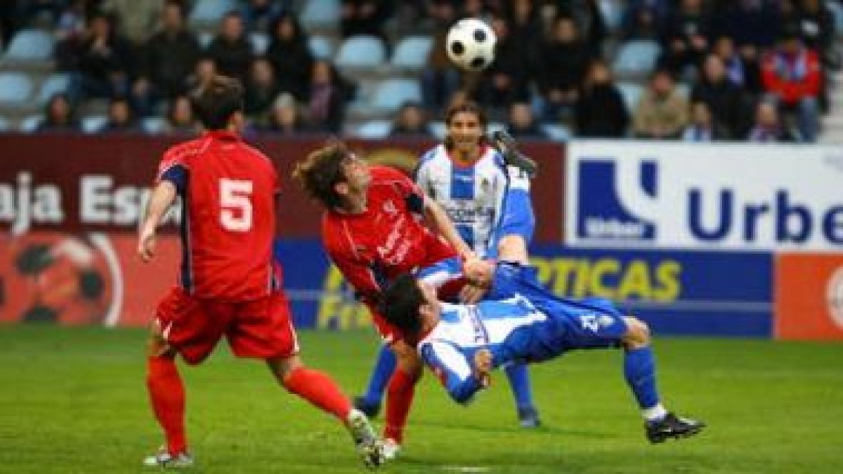 El jugador de la Deportiva, Jonathan Valle, intenta rematar acrobáticamente un balón rodeado de dos