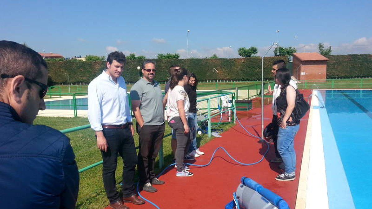 El alcalde observa la nueva instalación del robot que limpiará los fondos de las piscinas.