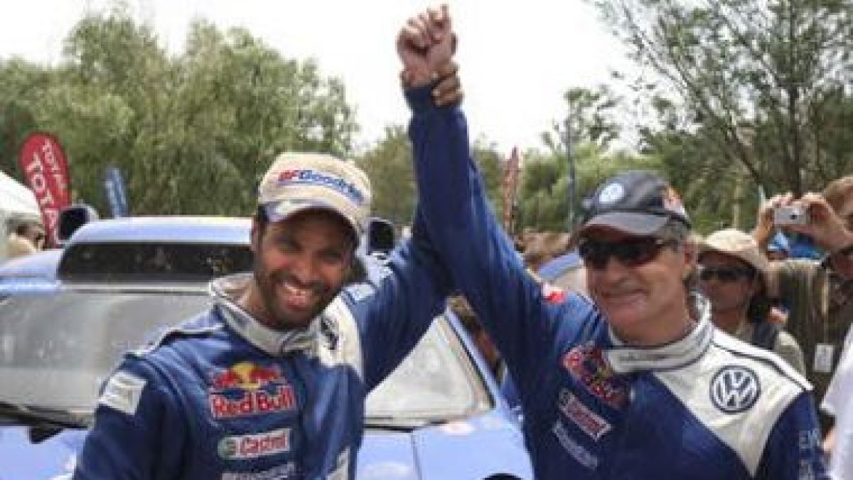 Sainz (d), ganador del Dakar 2010, levanta el brazo junto al qatarí Nasser, segundo.