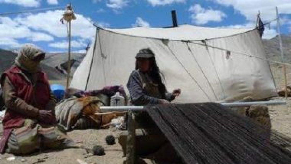 Dos mujeres tejen en un campamento nómada.