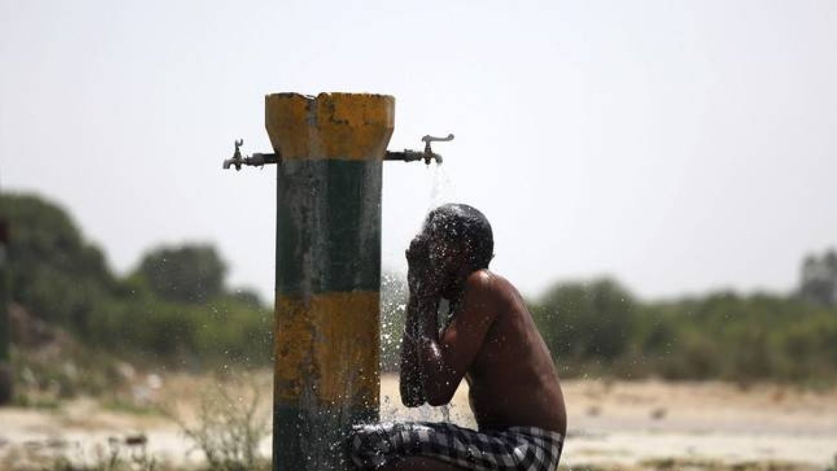 Un trabajador indio se refresca bajo un grifo una calurosa tarde en Amritsar (India).