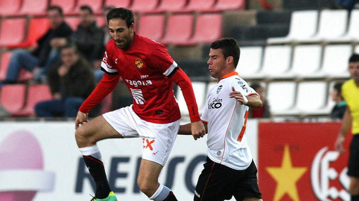 El defensa del Gimnàstic de Tarragona Juanjo lucha por un balón con el zaguero che Juan Bernat.