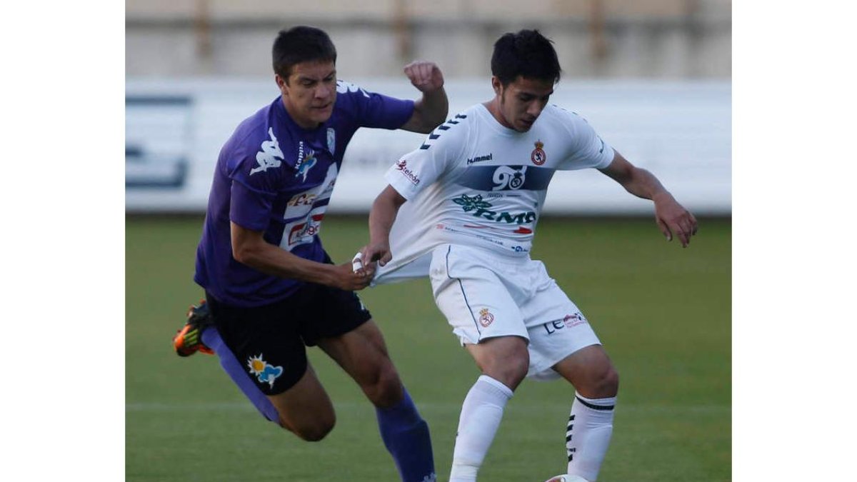 David Álvarez se lleva el balón a pesar del agarrón de un jugador bañezano
