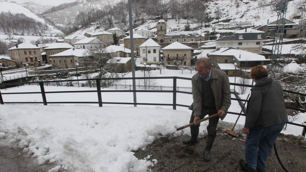 Dos vecinos de Barjas retiran ayer por la mañana nieve de la calle próxima a sus casas.