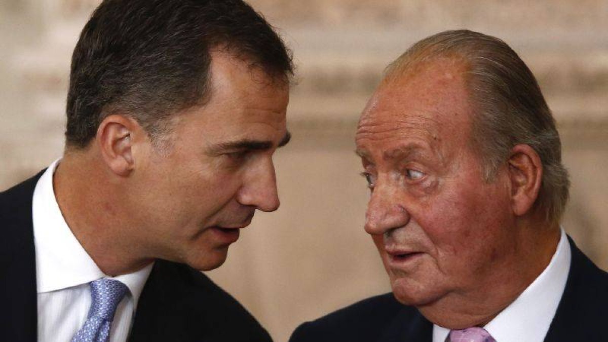 Juan Carlos dialoga con su hijo, ayer durante la firma de su abdicación.