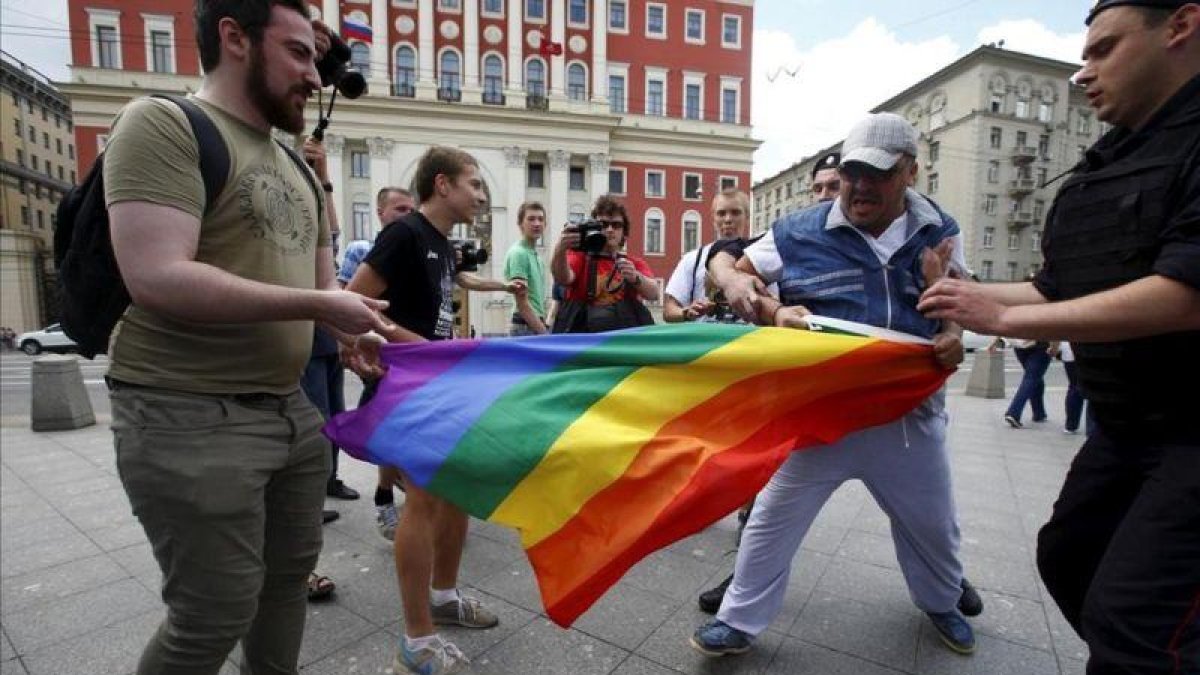 Manifestantes homófobos tratan de romper una bandera gay de un grupo de homosexuales en Moscú