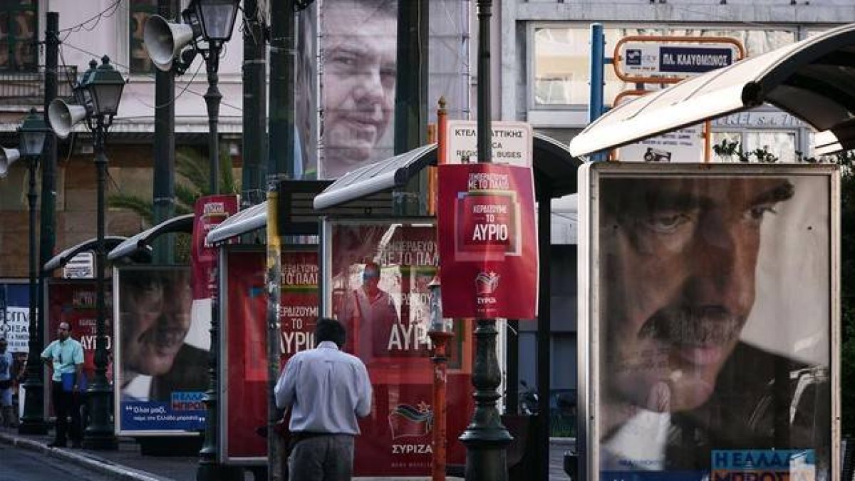 Un hombre pasa junto a un cartel electoral de Meïmarakis (derecha) y otro de Tsipras (arriba), este miércoles en Atenas.
