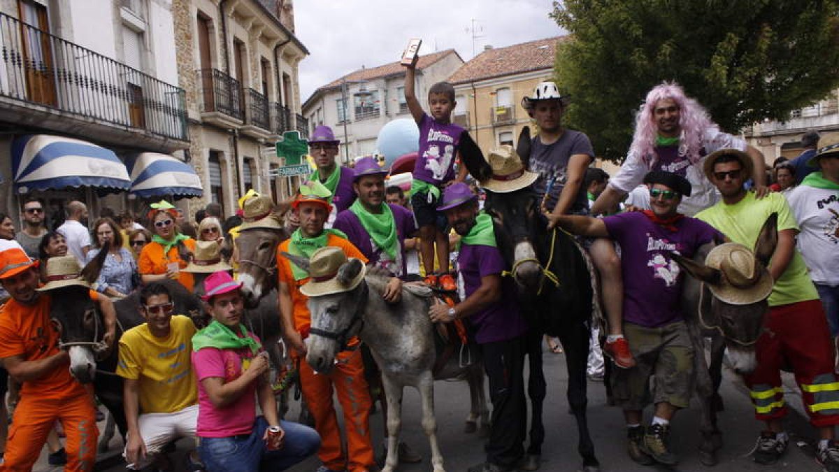 Los burros y participantes en la burrada de Boñar, Diego levanta el trofeo de ganador.